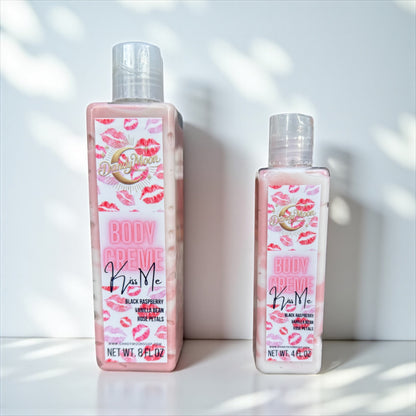 Two bottles of Body Creme Lotion in the scent kiss me with pink, the lotion bottles are clear and the lotion inside is white and reddish pink. the bottles stand on a white surface against a white background