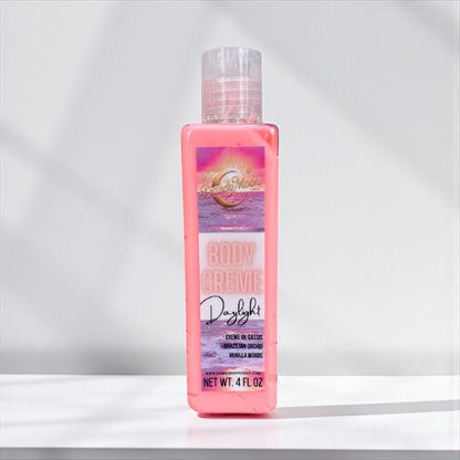 Bottle of 'Daylight' body creme lotion with a colorful label on a white background. the bottle of lotion is clear and the lotion inside it is coral color. 