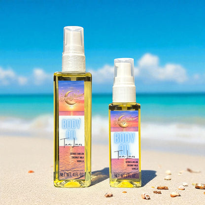 Two bottles of 'Body Oil Tan Lines scent' on a sandy beach with a blue sky and the ocean in the background