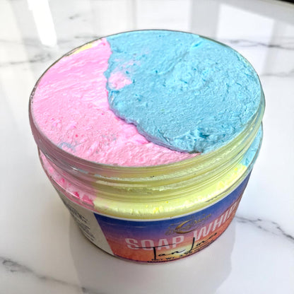 an open jar of soap whip, showing pink blue and yellow soap whip in a jar sitting on a white marble surface