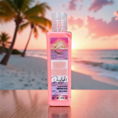 a bottle of body creme lotion in the scent daylight. the bottle is clear and the lotion inside it is a coral color. it is standing on a wood surface with a sandy beach in the background with palm trees in the background