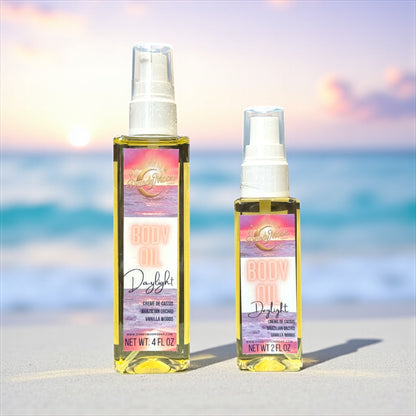 Two bottles of body oil, one is 2 ounces and one is 4 ounces, standing on a white sandy beach, with a blurred ocean background