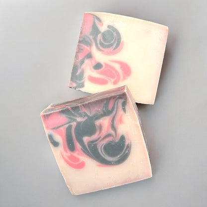 Two bars of swirled white, black and red pattern bar soap on a grey surface
