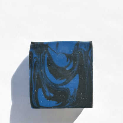 a bar of soap with blue and black swirls laying flat on a white surface