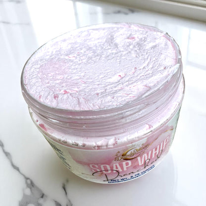 an open jar of pink bath soap whip sitting on a white marble surface