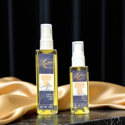Two bottles of Dandy Moon body oil, one is 2 ounces and one is 4 ounces, on a dark surface with a gold satin cloth in the background.