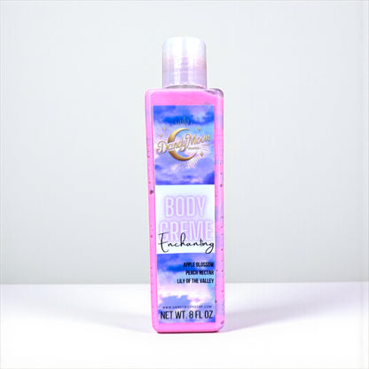 a bottle of body creme lotion in the scent enchanting. the bottle is clear and the lotion inside is swirls of purple and pink. the bottle stands on a white surface against a white background