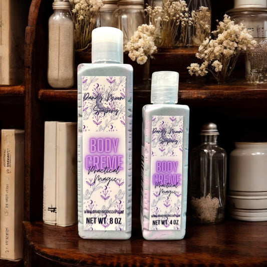 two bottles of DANDY moon soaperys body creme are displayed on a rustic wooden shelf with a backdrop of dried flowers and vintage glass jars. the bottles, one 8 ounces and one 4 ounces have a soft lavender label design featuring botanical illustrations. the product label reads body creme - practical magic showcasing Dandy Moon Soapery's dedication to natural, artisan body care. 